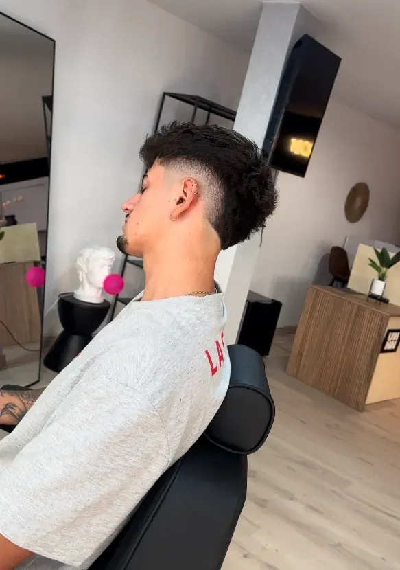 Hombre en silla de barbero con un corte de pelo degradado.