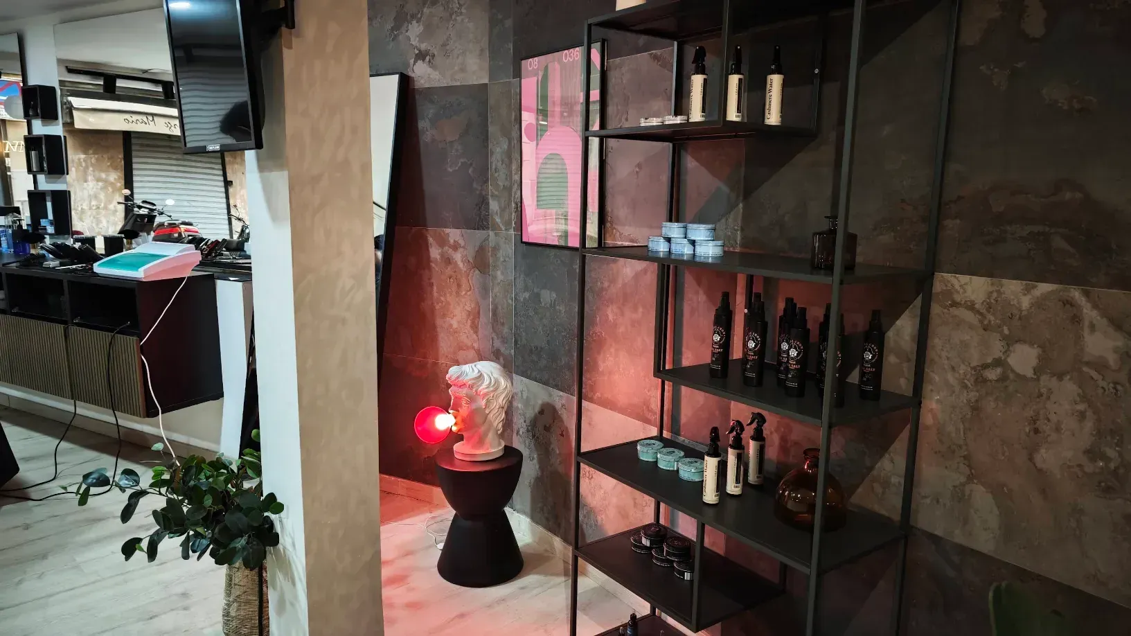 Interior de una pequeña tienda con estantes de productos, un taburete decorativo y paredes texturizadas.