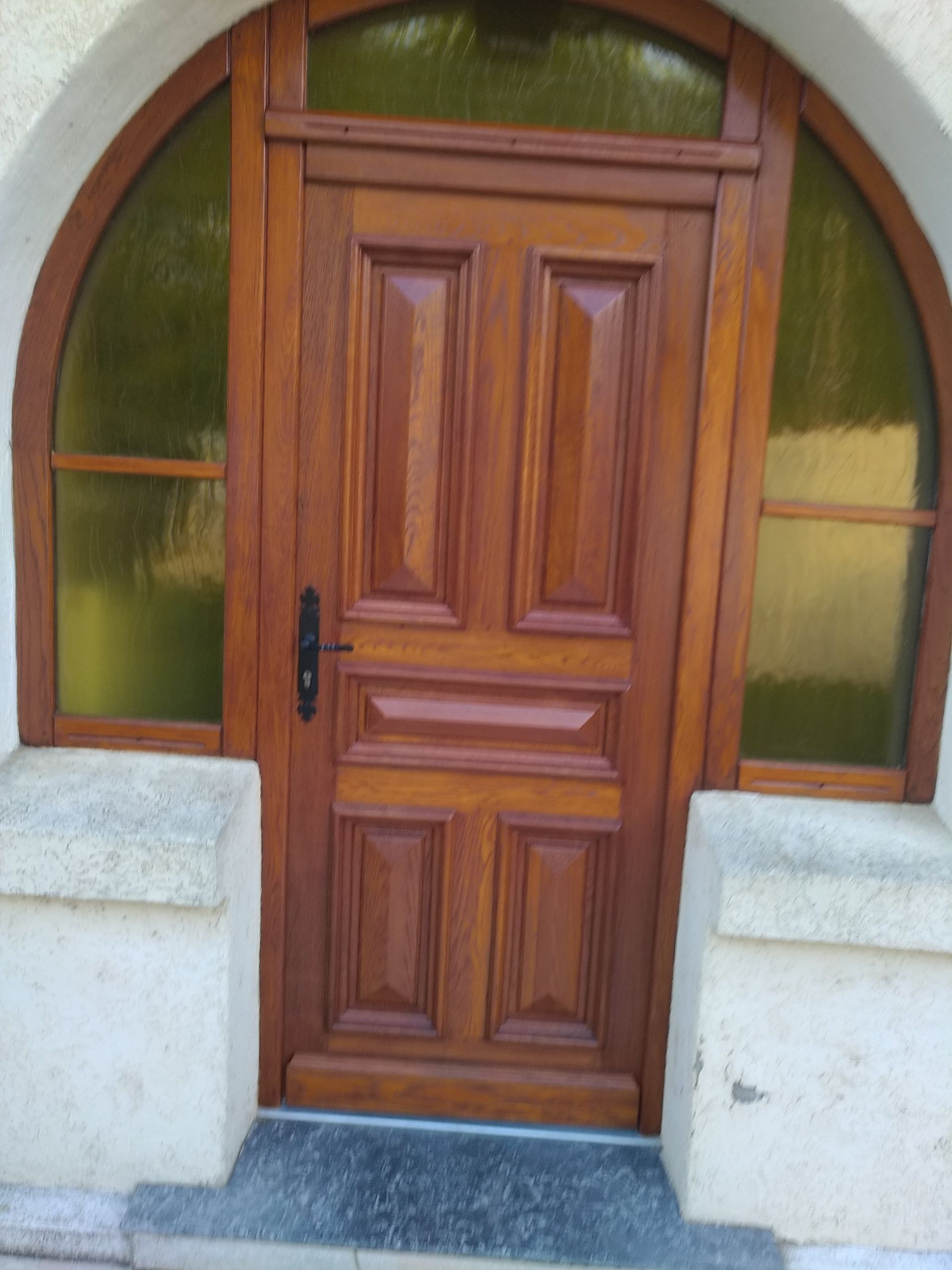 Porte en bois avec fenêtres cintrées, teintée en brun.