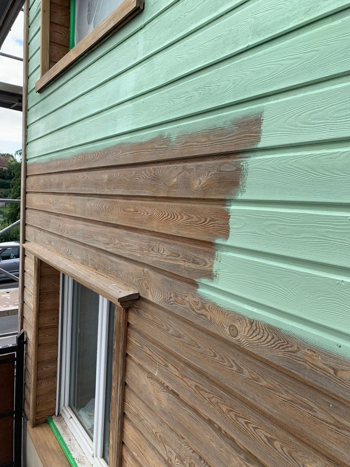 Le revêtement extérieur de la maison est en cours de peinture : brun sur vert.