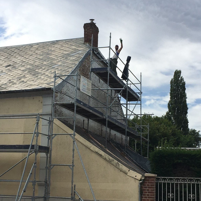 Des ouvriers sur un échafaudage en train de repeindre une façade.