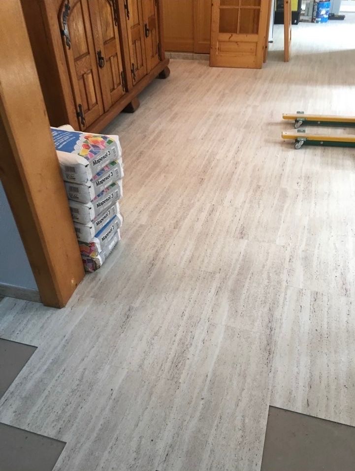 Sol clair avec des sacs empilés contre une armoire en bois et une poutre de soutien.