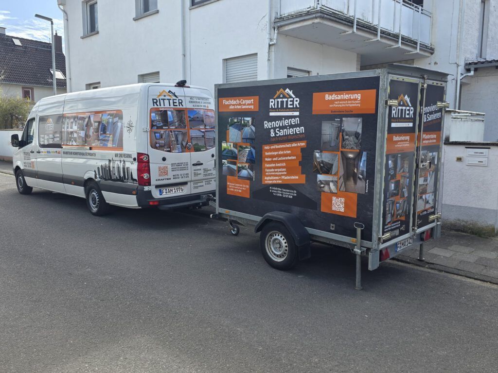 Ein weißer Lieferwagen mit schwarzem Anhänger, beide mit Firmenlogos, parkt auf einer Straße in der Nähe eines Gebäudes.