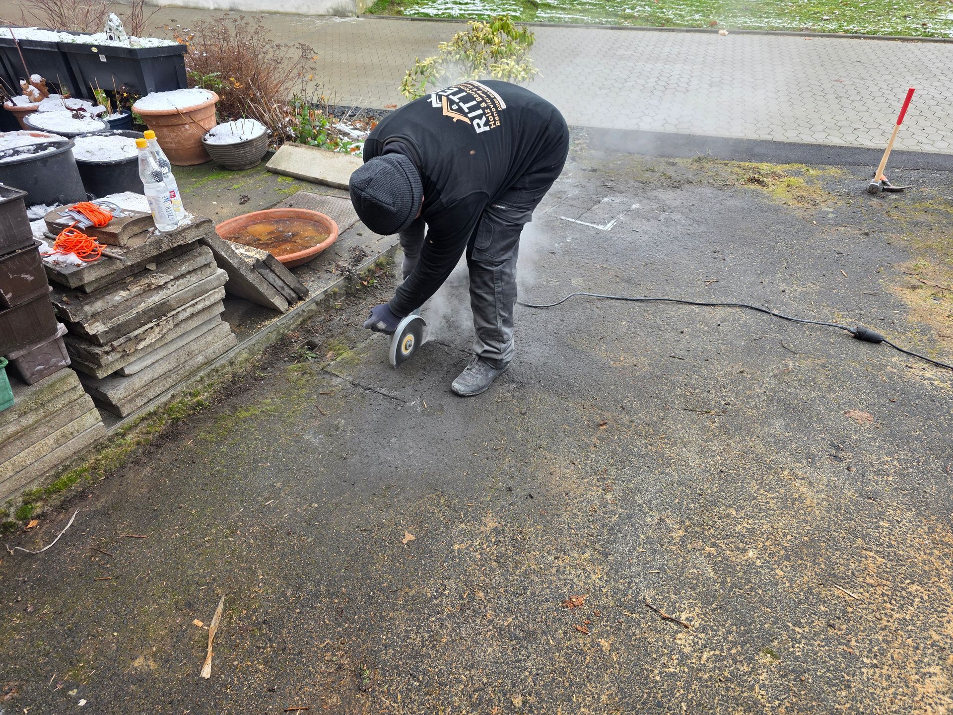 Eine Person schneidet im Freien Beton neben gestapelten Fliesen.