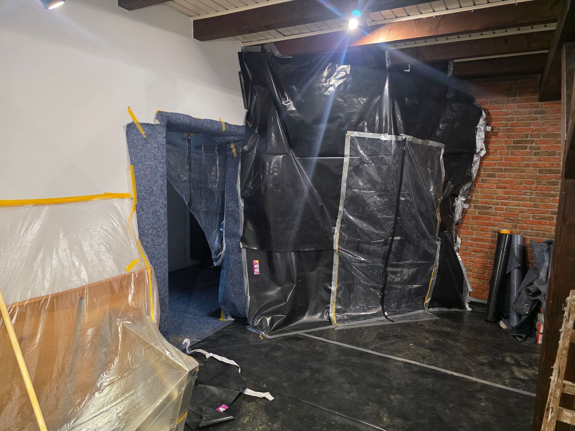 Raum mit Wänden und Öffnungen, die mit schwarzer Plastikfolie und blauer Schaumstoffpolsterung verkleidet sind.