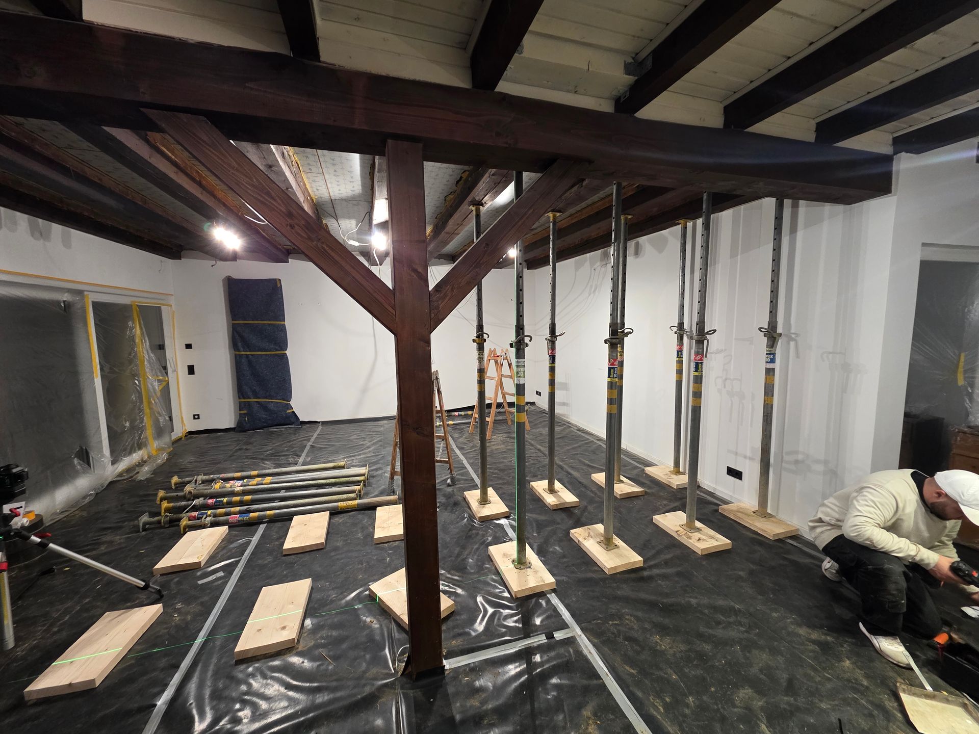 Die Innenrenovierung ist im Gange; man sieht Stützpfeiler unter einem Holzbalken. Rechts arbeitet eine Person.