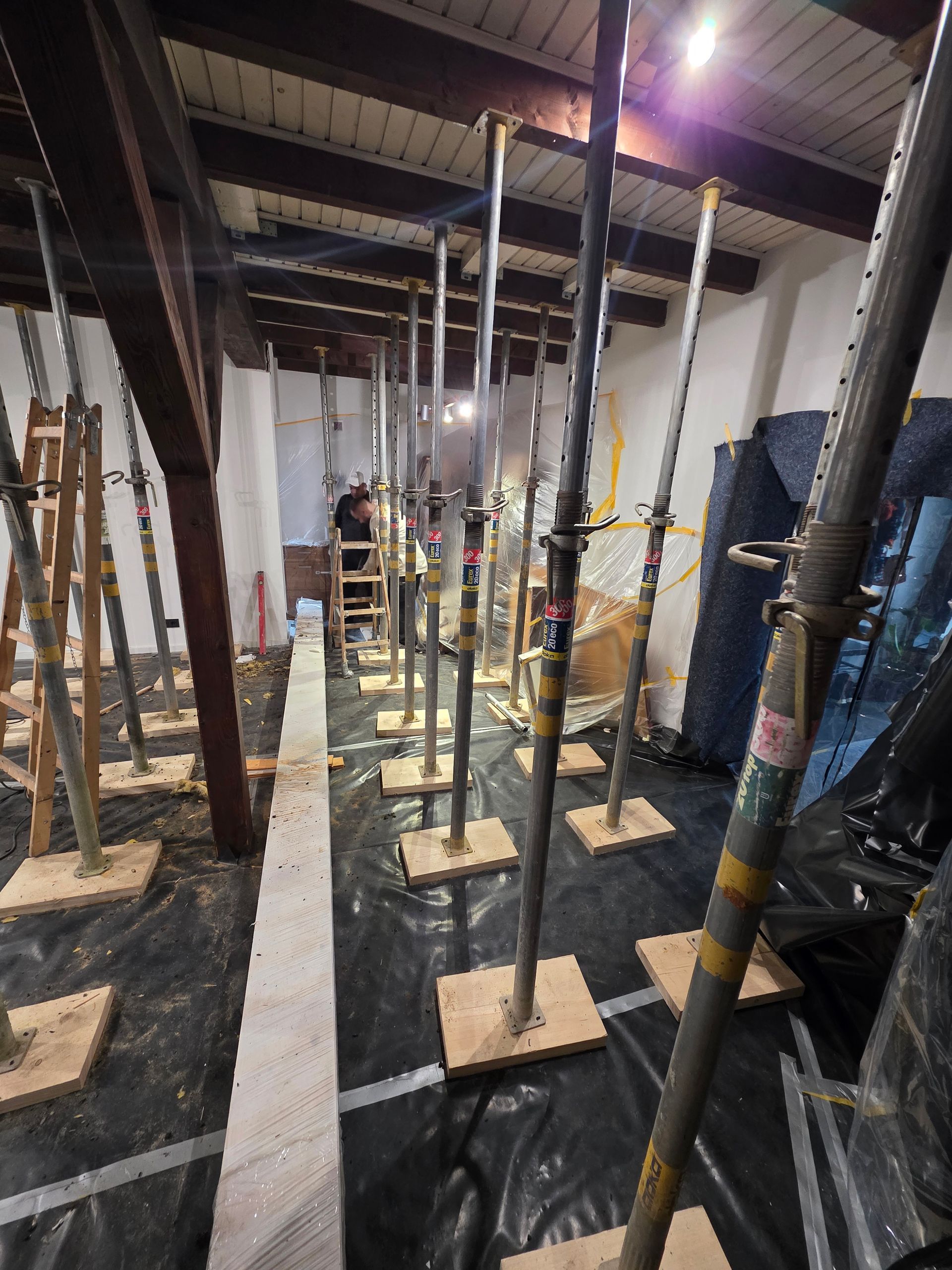 Innenraum mit Stützfüßen, die die Decke abstützen. Eine schwarze Plane bedeckt den Boden.