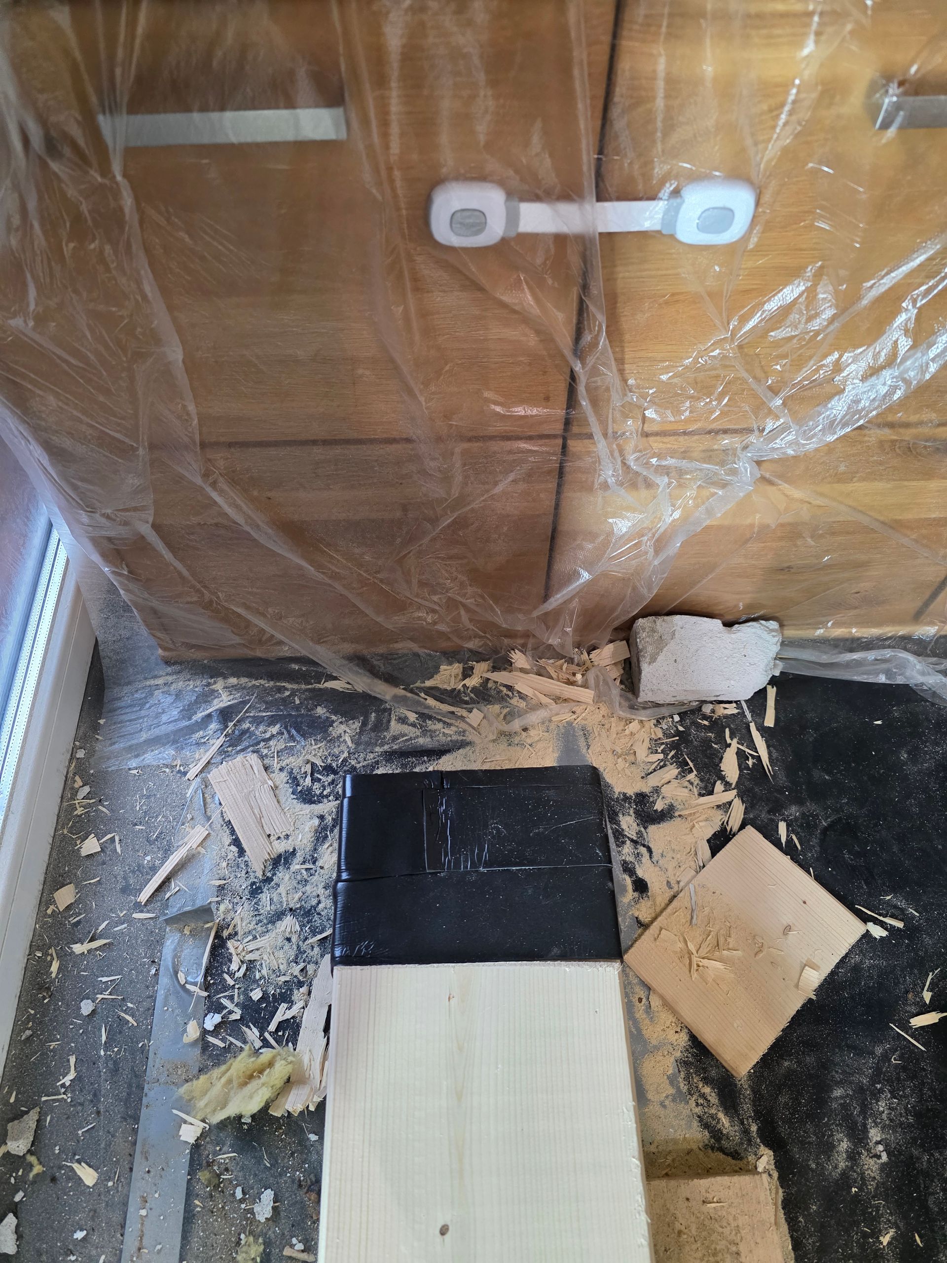 Holzschrank mit Kindersicherung, Plastikfolie und Bodenstreu.