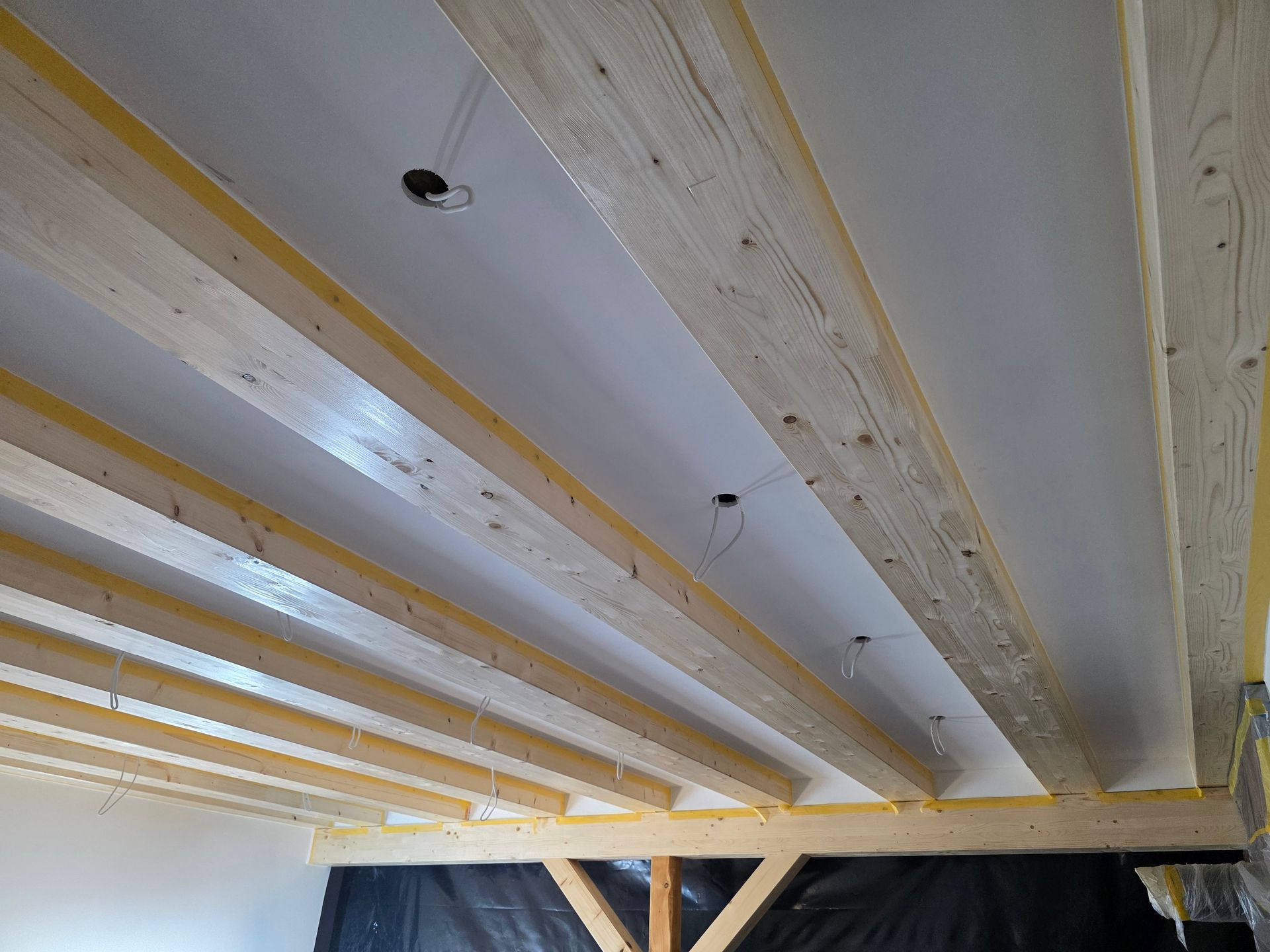 Holzbalken und weiße Deckenkonstruktion mit sichtbaren Kabeln.