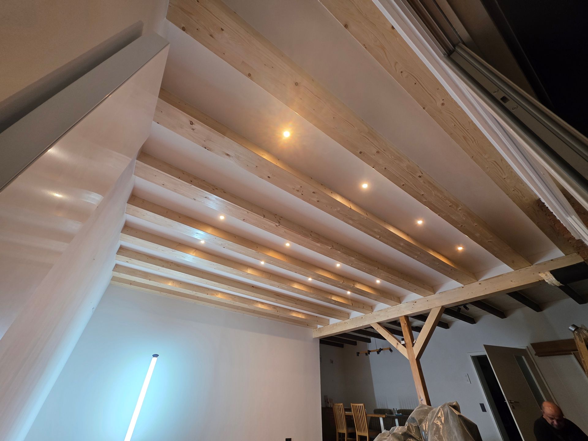 Holzbalkendecke mit Einbauleuchten in einem modernen Interieur, weiße Wände, abgewinkelte Struktur.