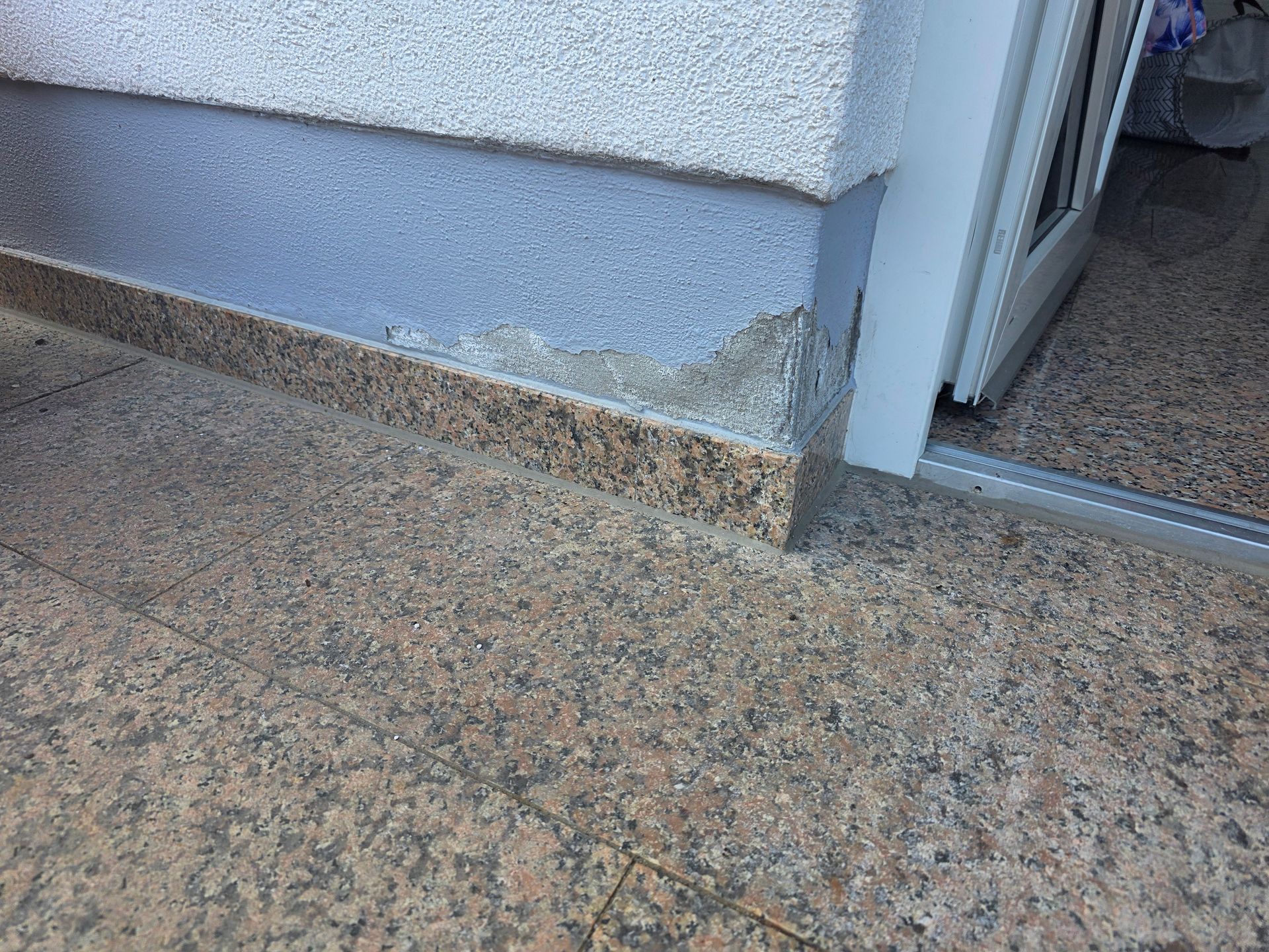 Eingangsstufe aus Granit neben einer Türöffnung mit Schwelle und Sockelleiste.