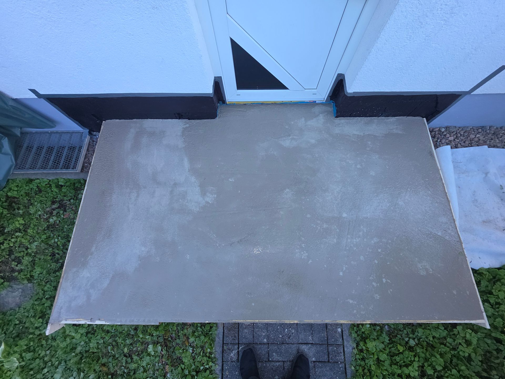 Graue Fußmatte auf einer kleinen schwarzen Matte vor einer weißen Tür