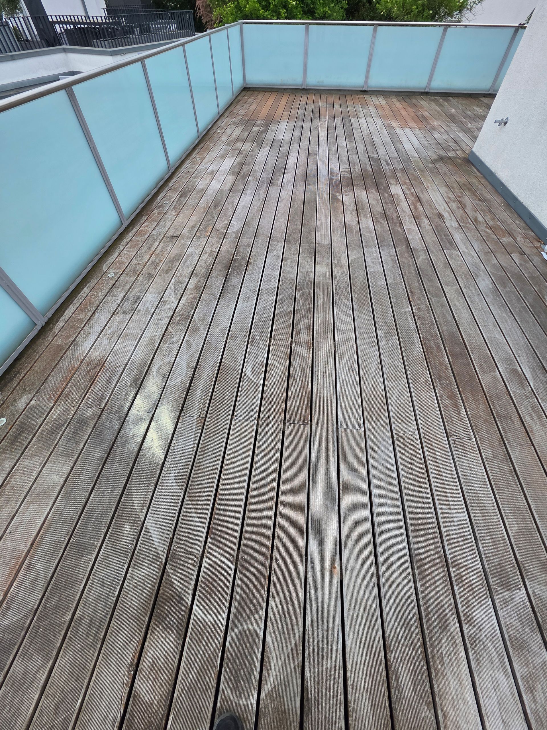 Verwitterte Holzterrasse mit hellblauem Geländer auf einem Balkon oder einer Dachterrasse