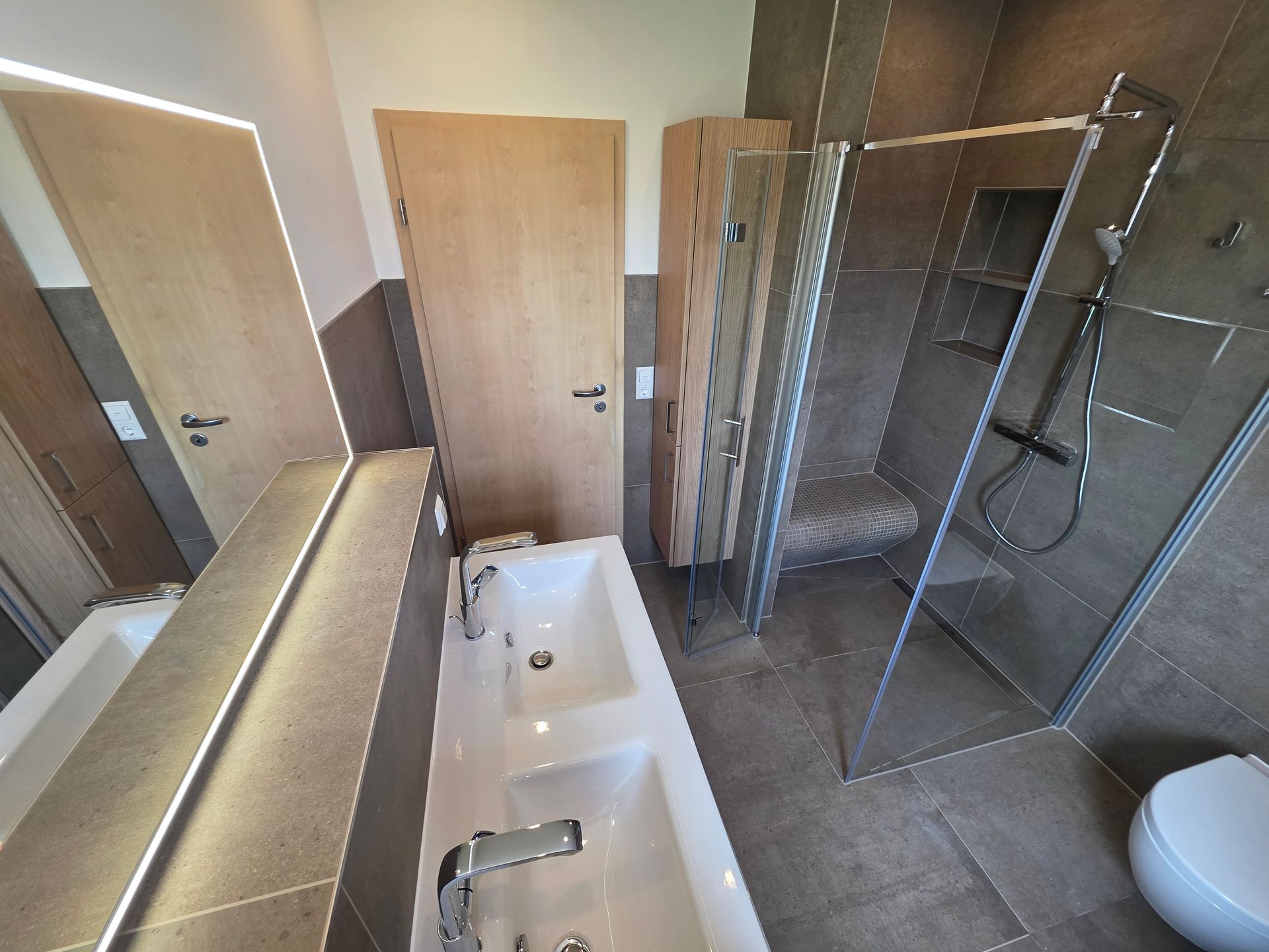Modernes Badezimmer mit Badewanne, Dusche, Waschbecken, großem Spiegel und gefliesten Wänden