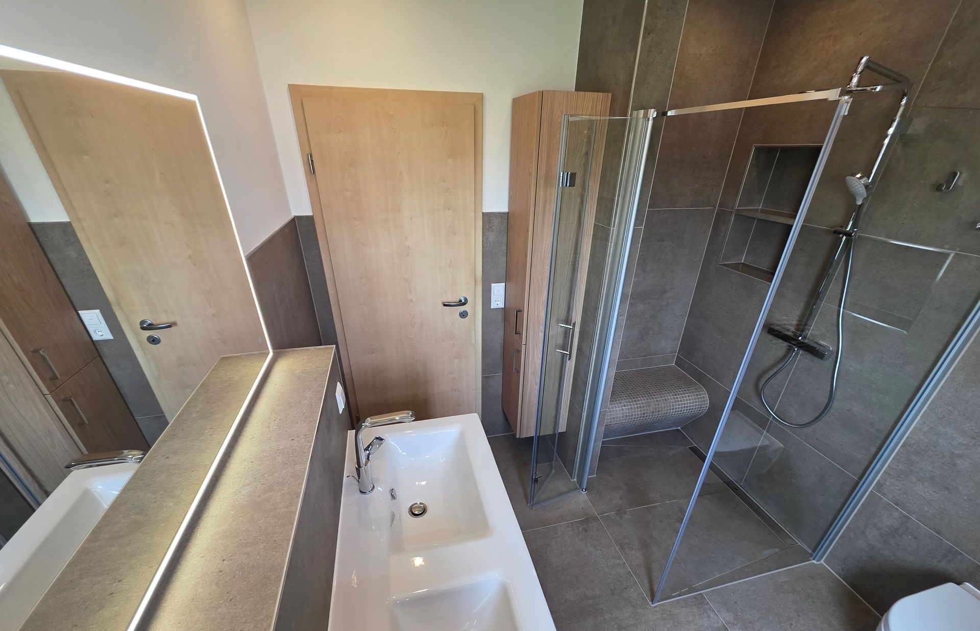 Modernes Badezimmer mit Badewanne, Duschkabine, Waschtischspiegel und Holztüren