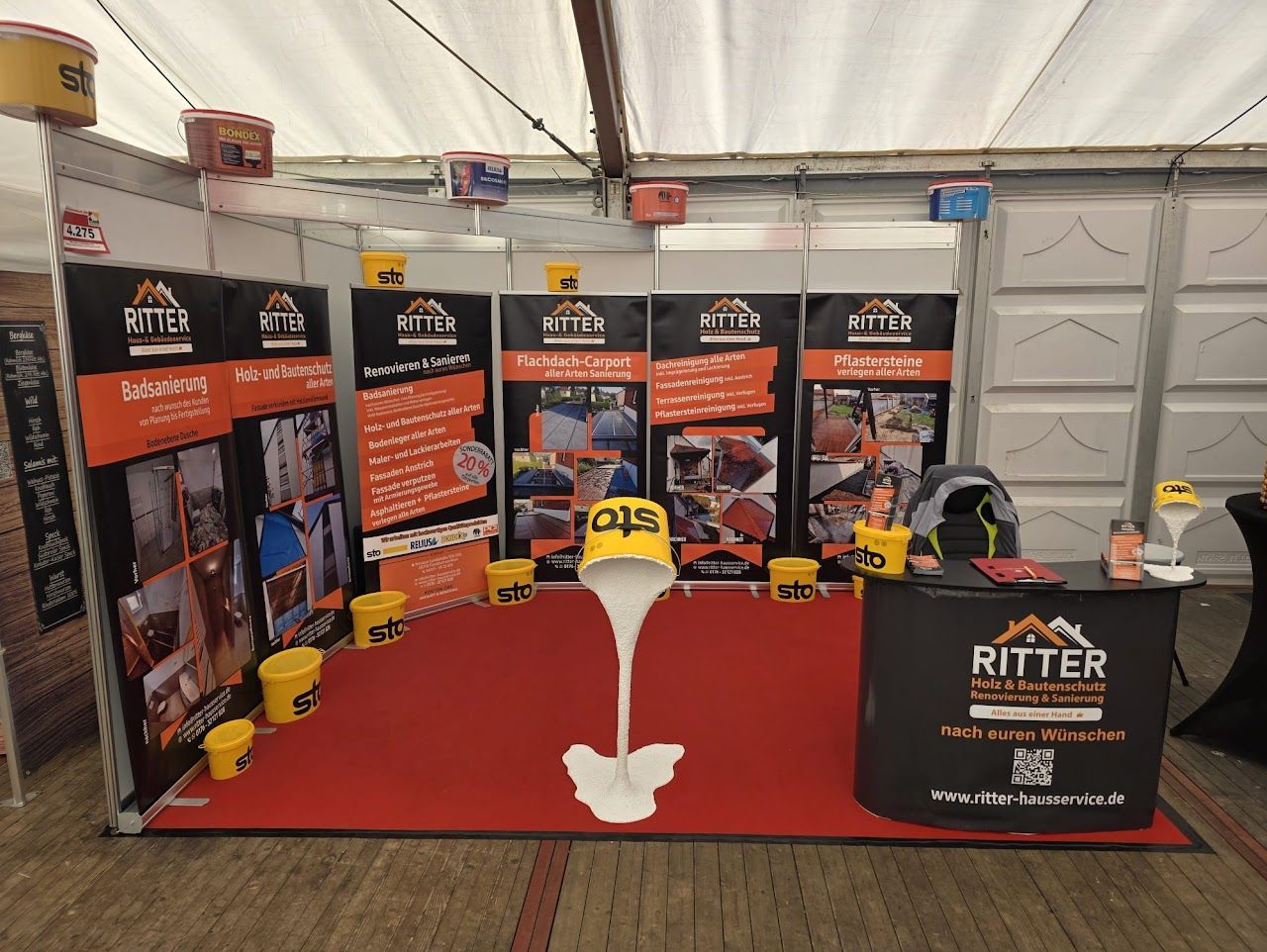 Messestand für Ritter mit orangefarbenem, schwarzem und weißem Branding zur Präsentation der Produkte.