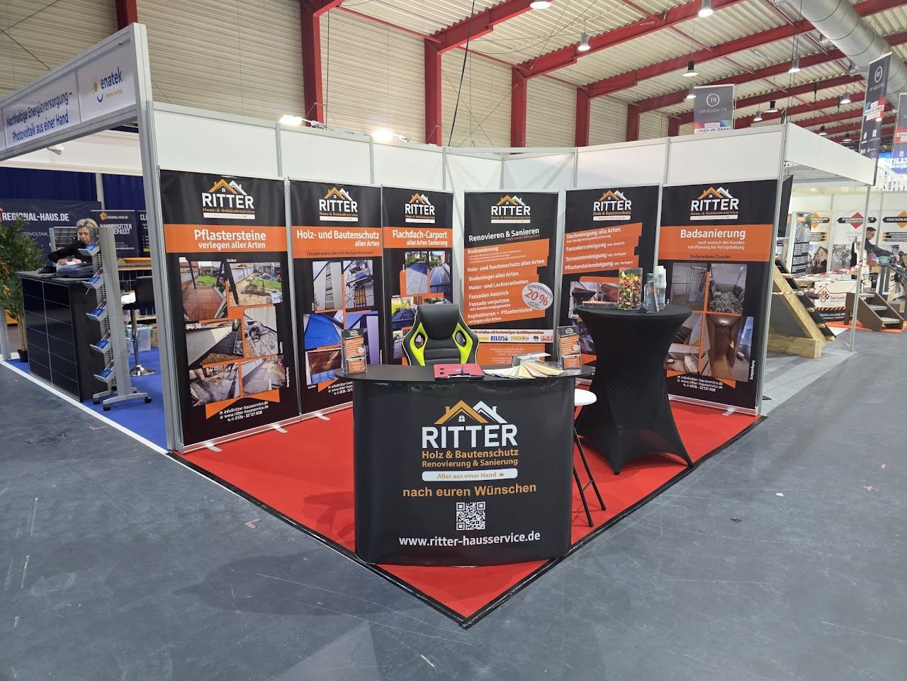 Messestand mit Ritter-Branding. Präsentationstafeln mit Produktfotos. Roter Teppich, schwarzer Tisch.
