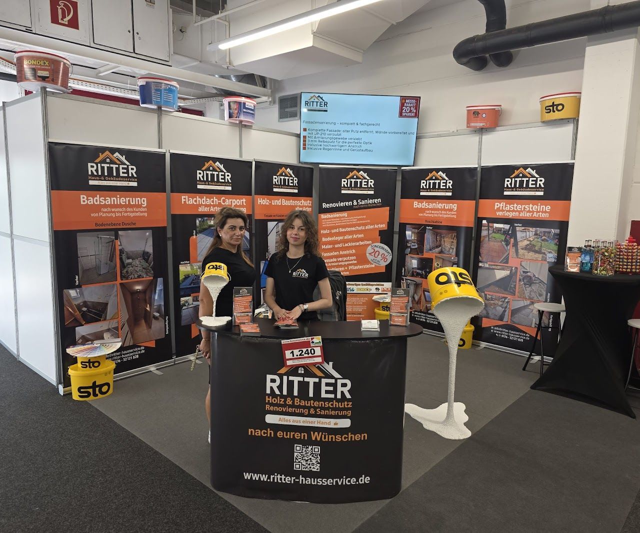 Zwei Frauen stehen mit Werbematerialien an einem Messestand von Ritter. Farbschema: Schwarz und Orange.