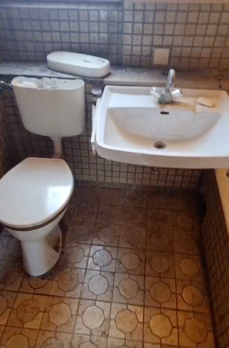 Kleines gefliestes Badezimmer mit Toilette, Waschbecken und gemusterten Bodenfliesen.