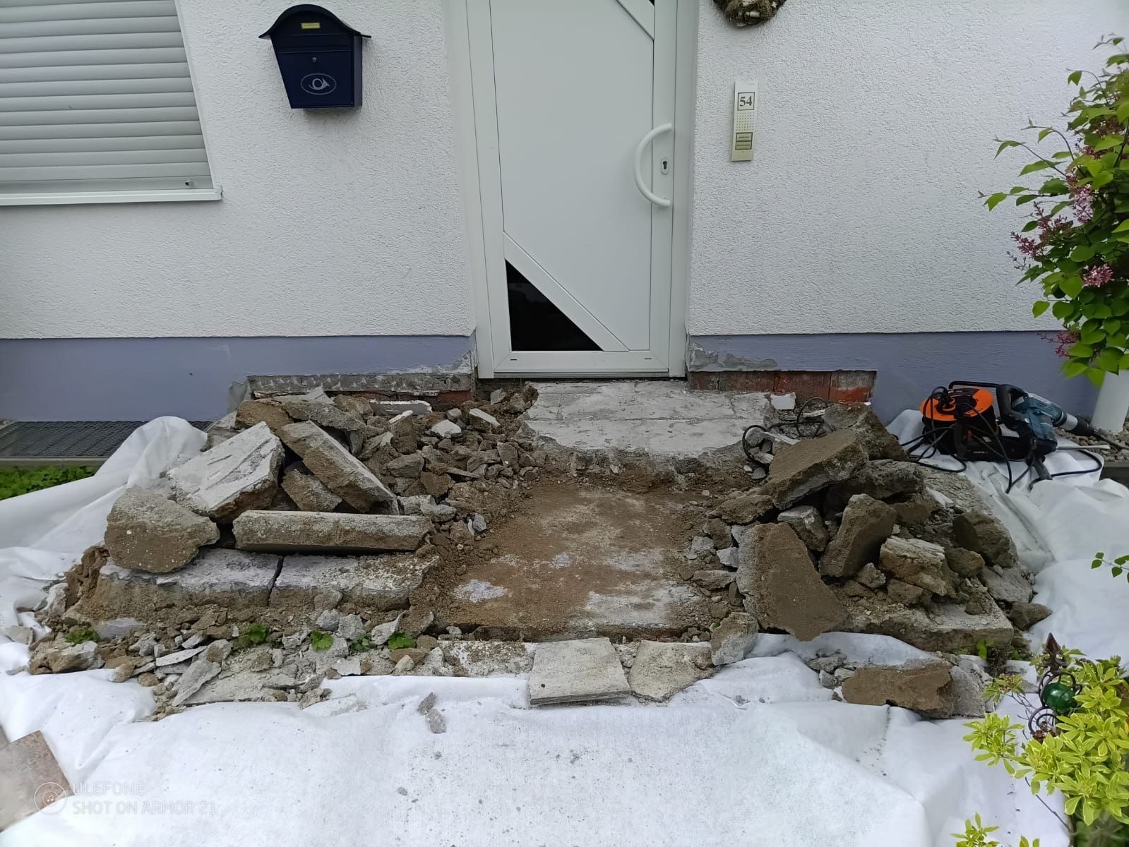 Teilweise abgerissene Eingangstreppe mit zerbrochenen Betonplatten und Schutt am Hauseingang