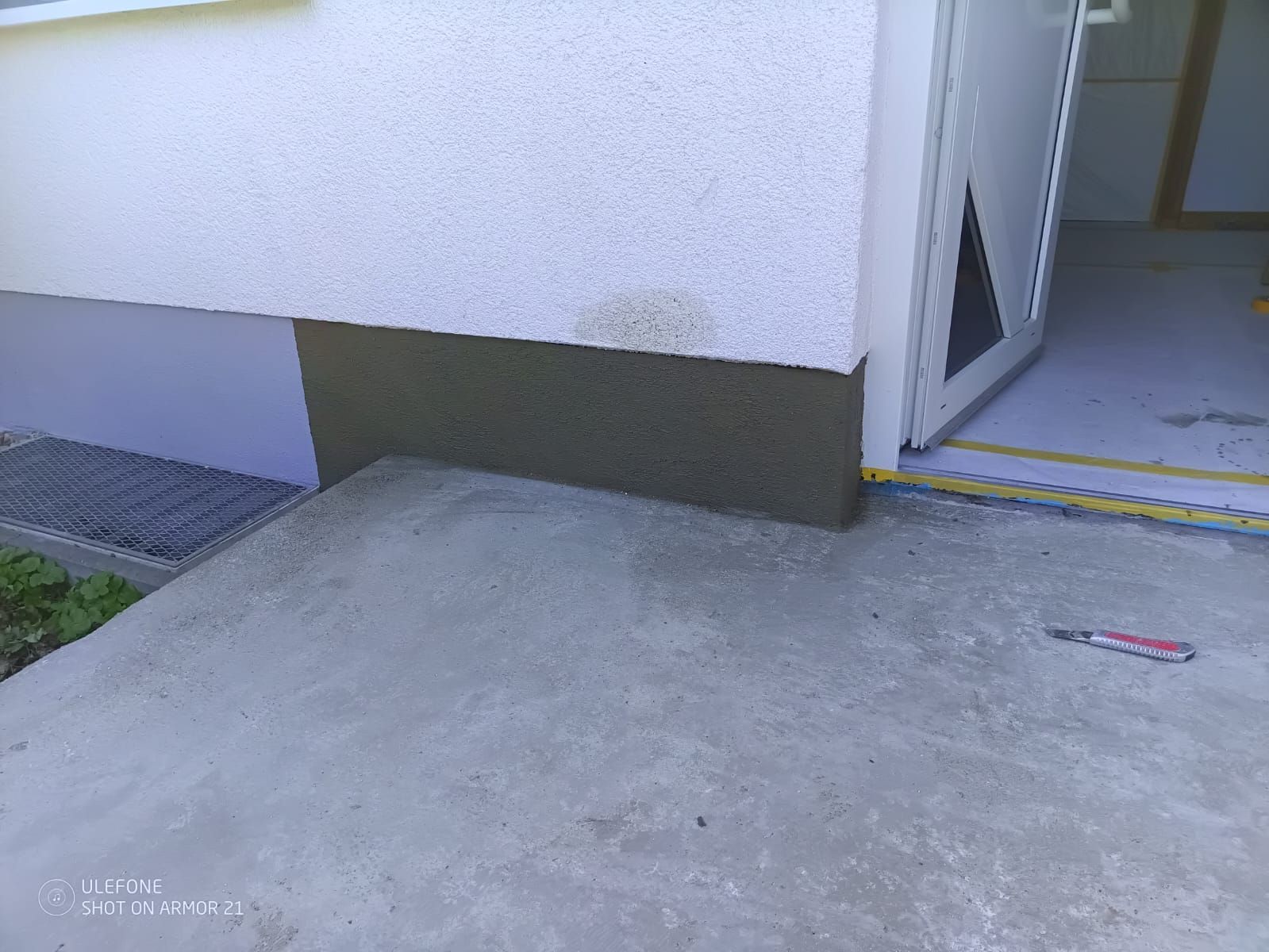 Betonrampe neben einem Gebäudeeingang mit offener Tür und gelbem Schwellenstreifen