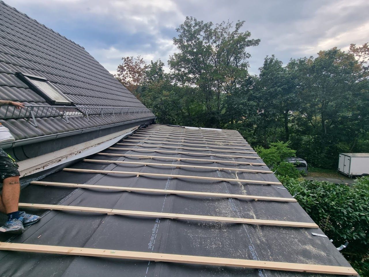 Dach im Bau; schwarze Ziegel, Holzbalken, schwarze Unterspannbahn.