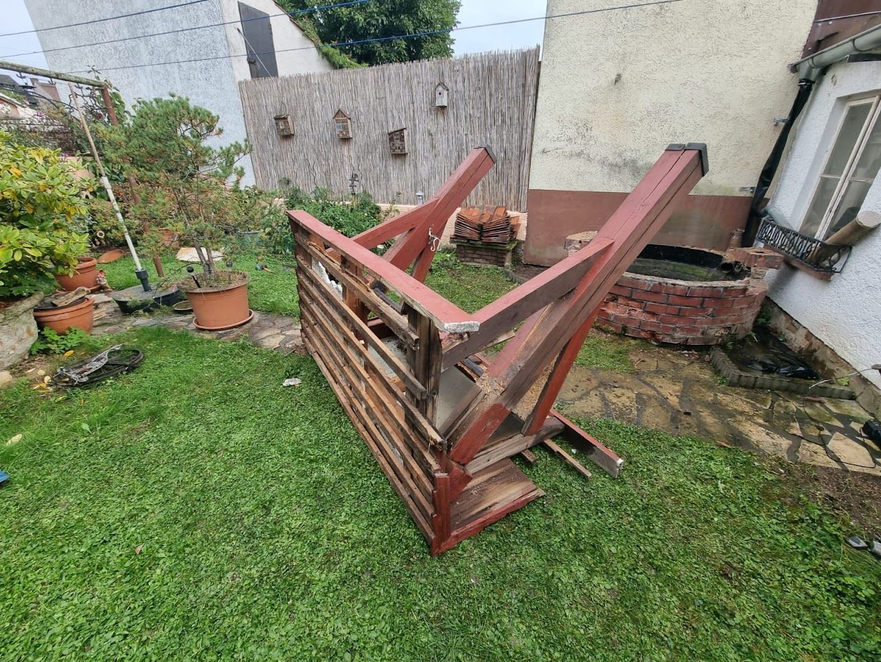 Auf einer Rasenfläche in der Nähe eines Hauses ist ein Holzzaun umgestürzt.
