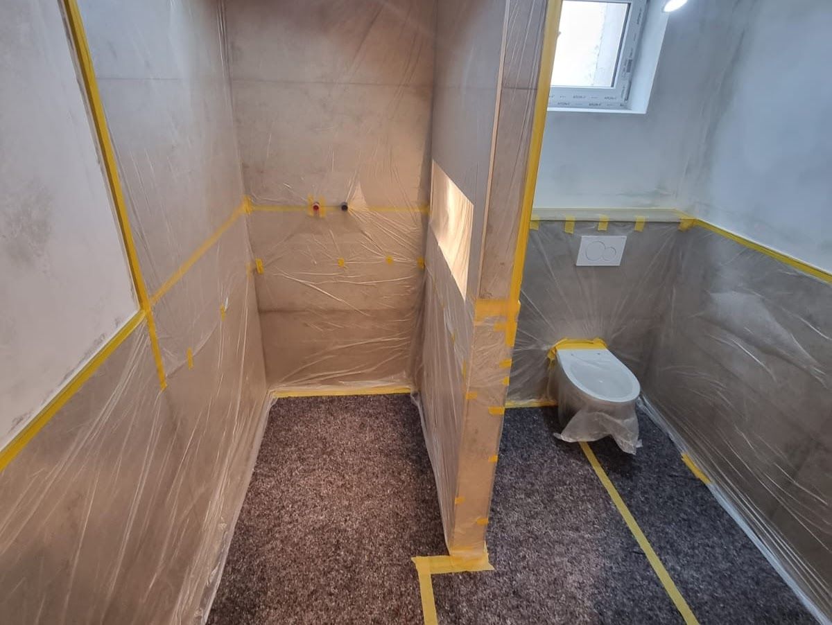 Badezimmer-Umbau: Die Wände sind mit Plastikfolie und Klebeband verkleidet; Toilette und Boden sind abgedeckt.