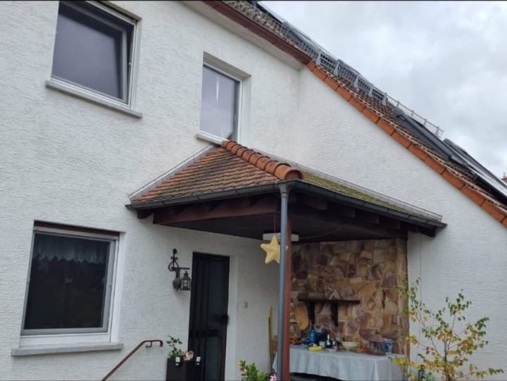 Weißes Haus mit einer kleinen Veranda über dem Eingang; das Dach ist mit Terrakotta-Ziegeln gedeckt.