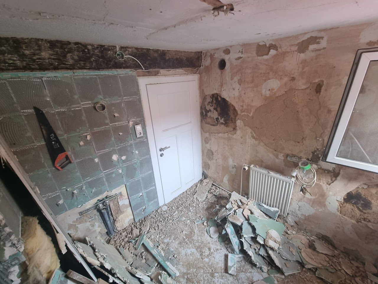 Ein Raum, der gerade renoviert wird, mit freiliegenden Wänden, Bauschutt und Werkzeugen.