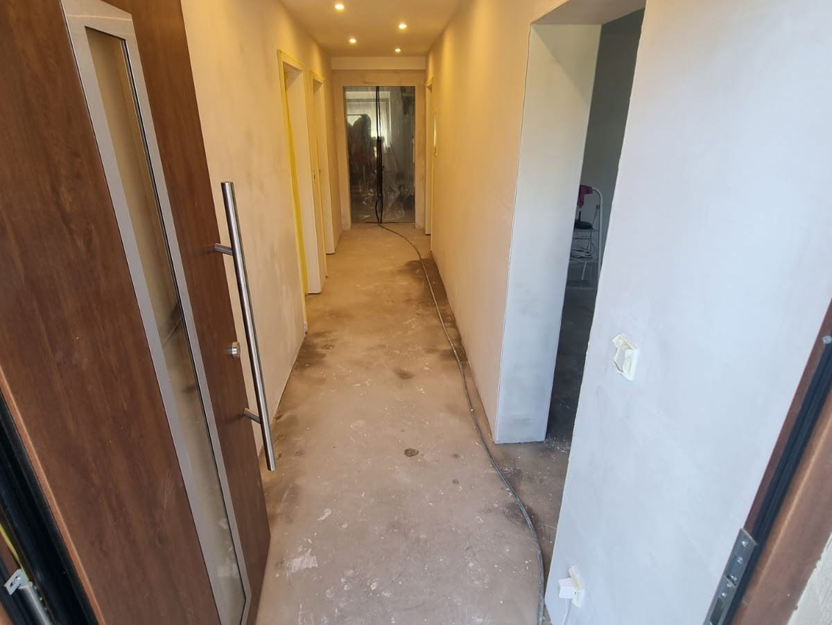 Schmaler Flur mit Türen, unverputzten Wänden und Betonboden.