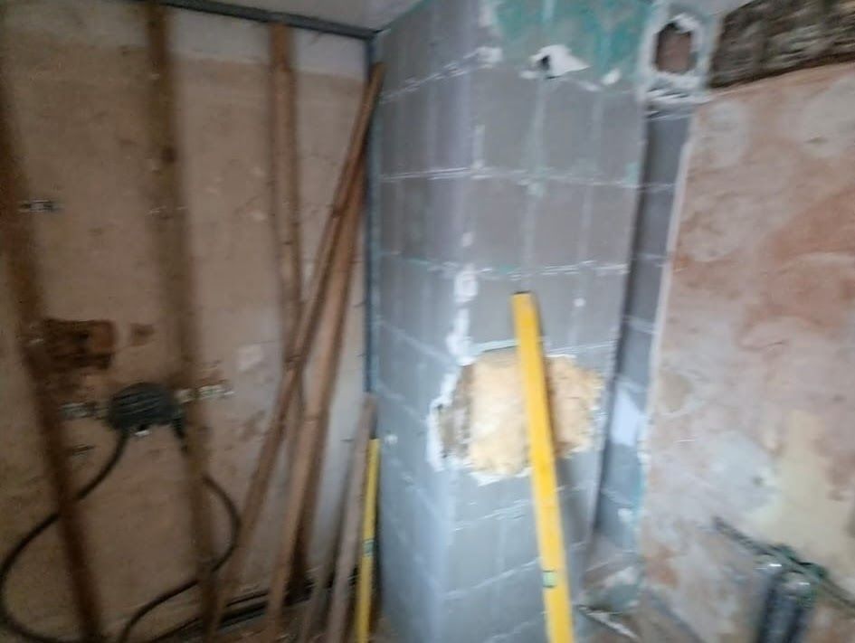 Baustelle mit freiliegenden Wandständern, gefliester Säule, Wasserwaage und elektrischer Verkabelung.