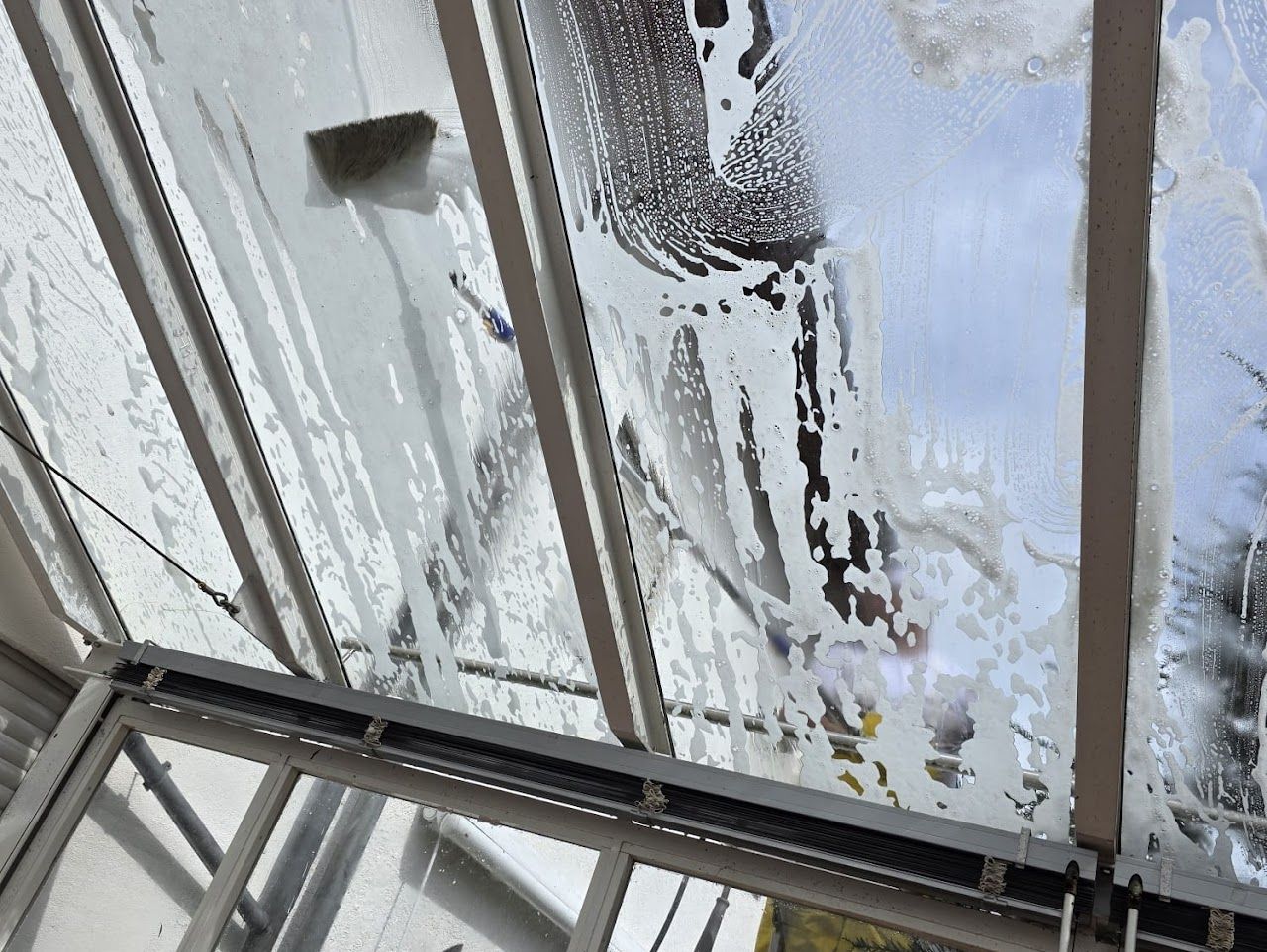 Das Dach eines Gewächshauses aus Glas mit Seifenwasser reinigen.