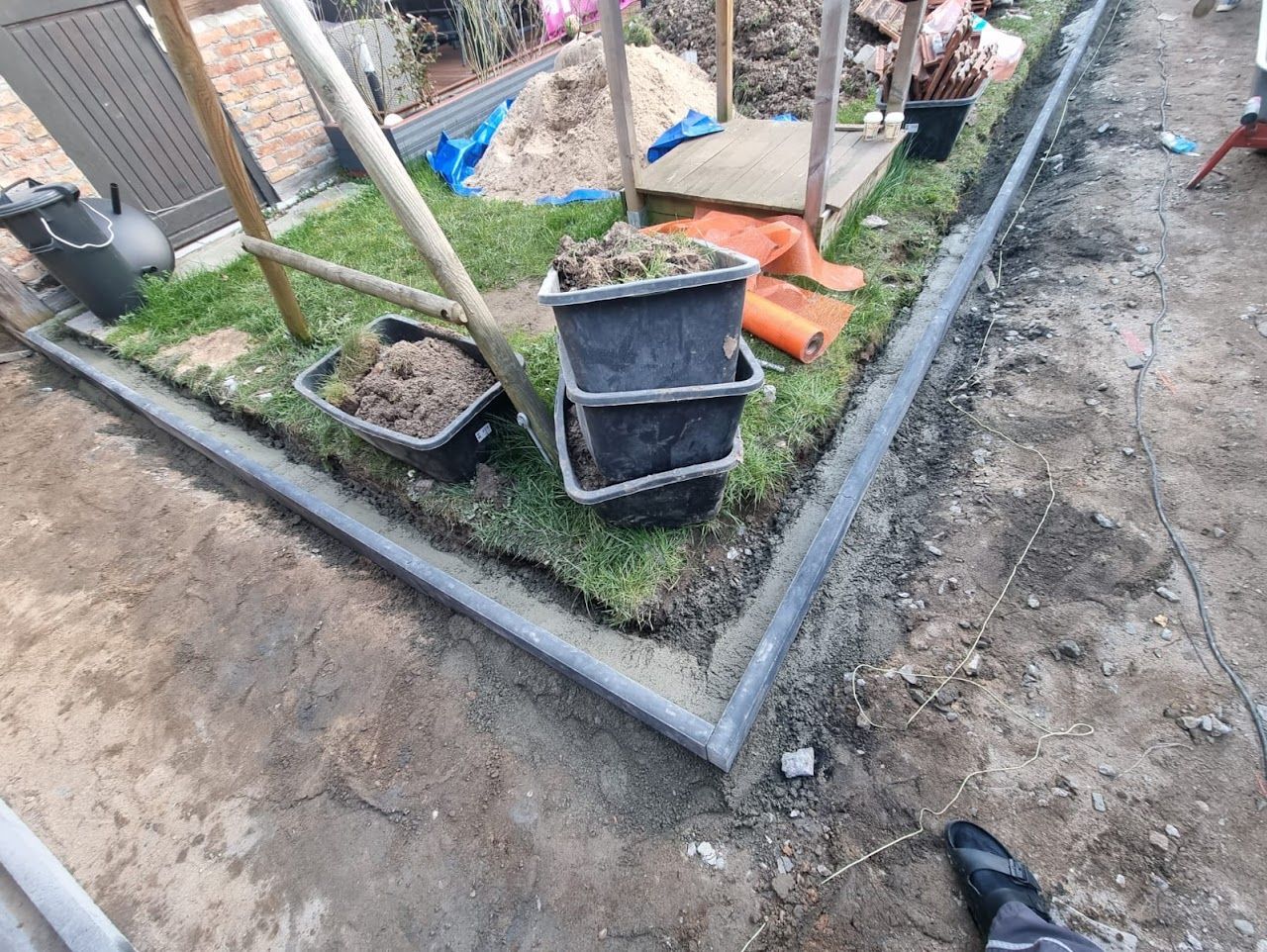 Bau eines Gartenbeets mit Betonrand und Eimern mit Erde, aufgestellt im Freien.