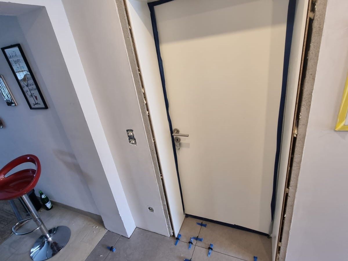 Weiße Innentür mit silbernem Griff und dunkelblauem Rahmen in einem Flur.