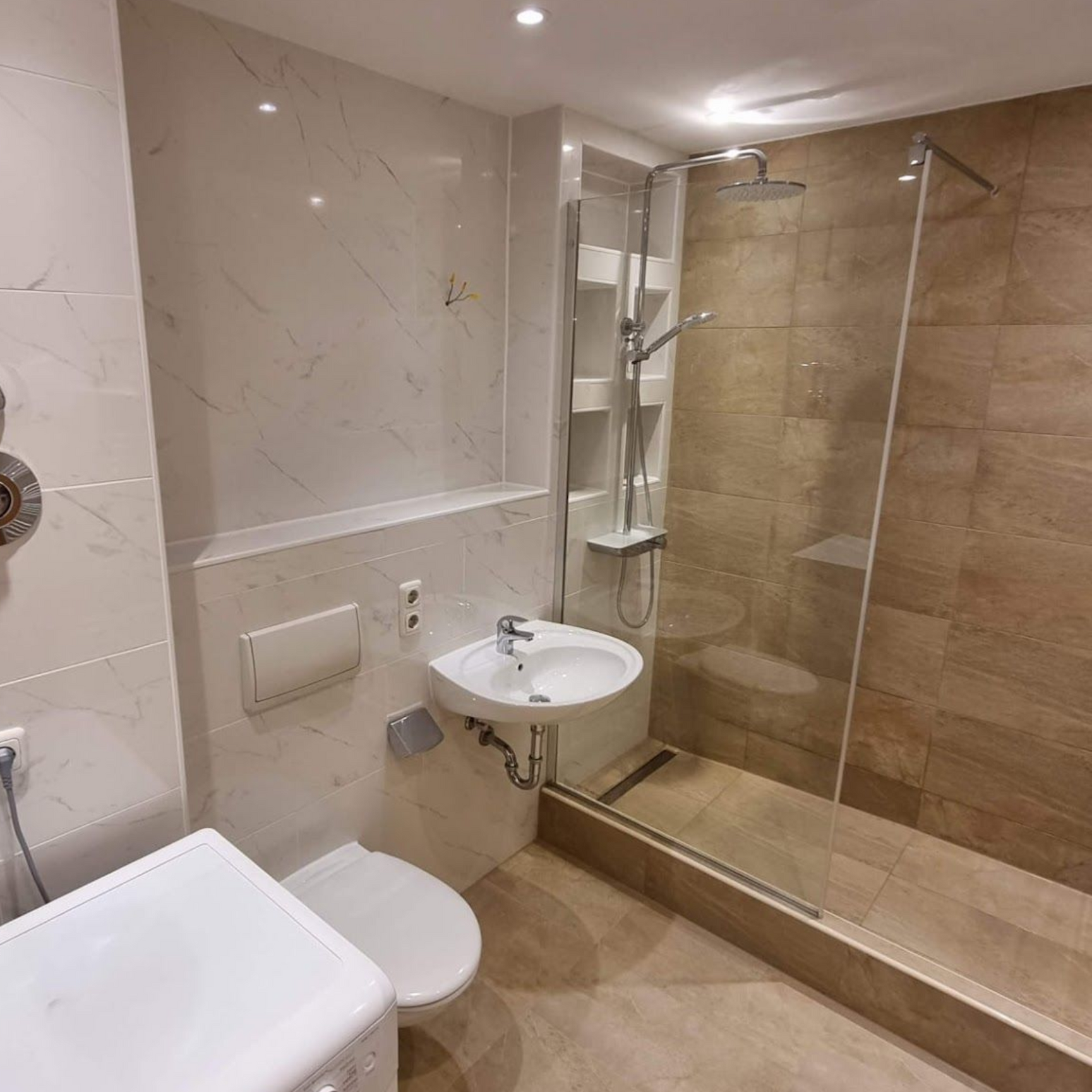 Modernes Badezimmer mit WC, wandmontiertem Waschbecken und ebenerdiger Dusche mit Glastrennwand