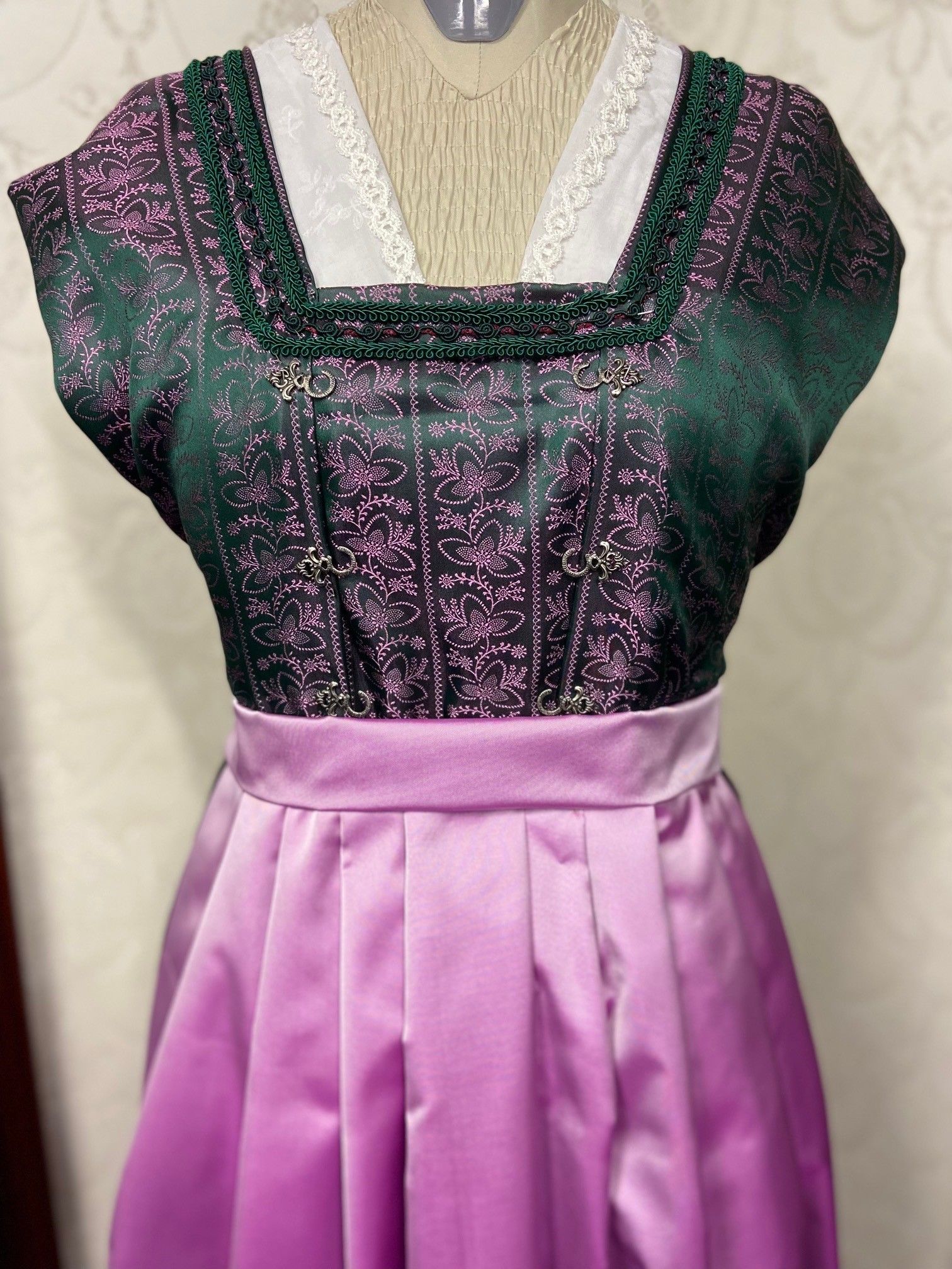 An einer Schaufensterpuppe hängt ein lila-grünes Kleid.