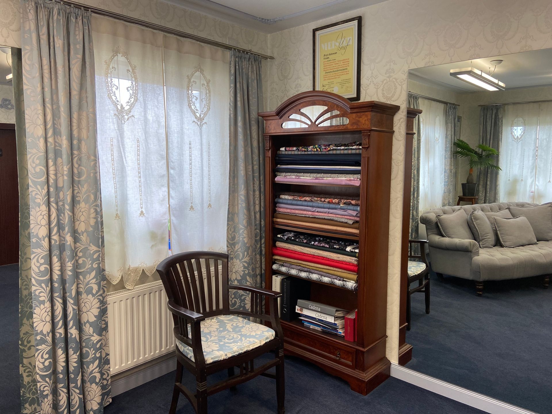 Ein Zimmer mit Couch, Sessel, Regal und Spiegel.