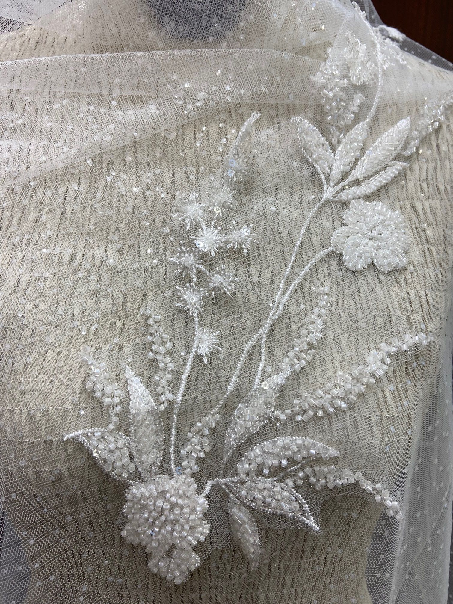 Eine Nahaufnahme eines Stücks Spitze mit Blumen und Blättern auf einer Schaufensterpuppe.