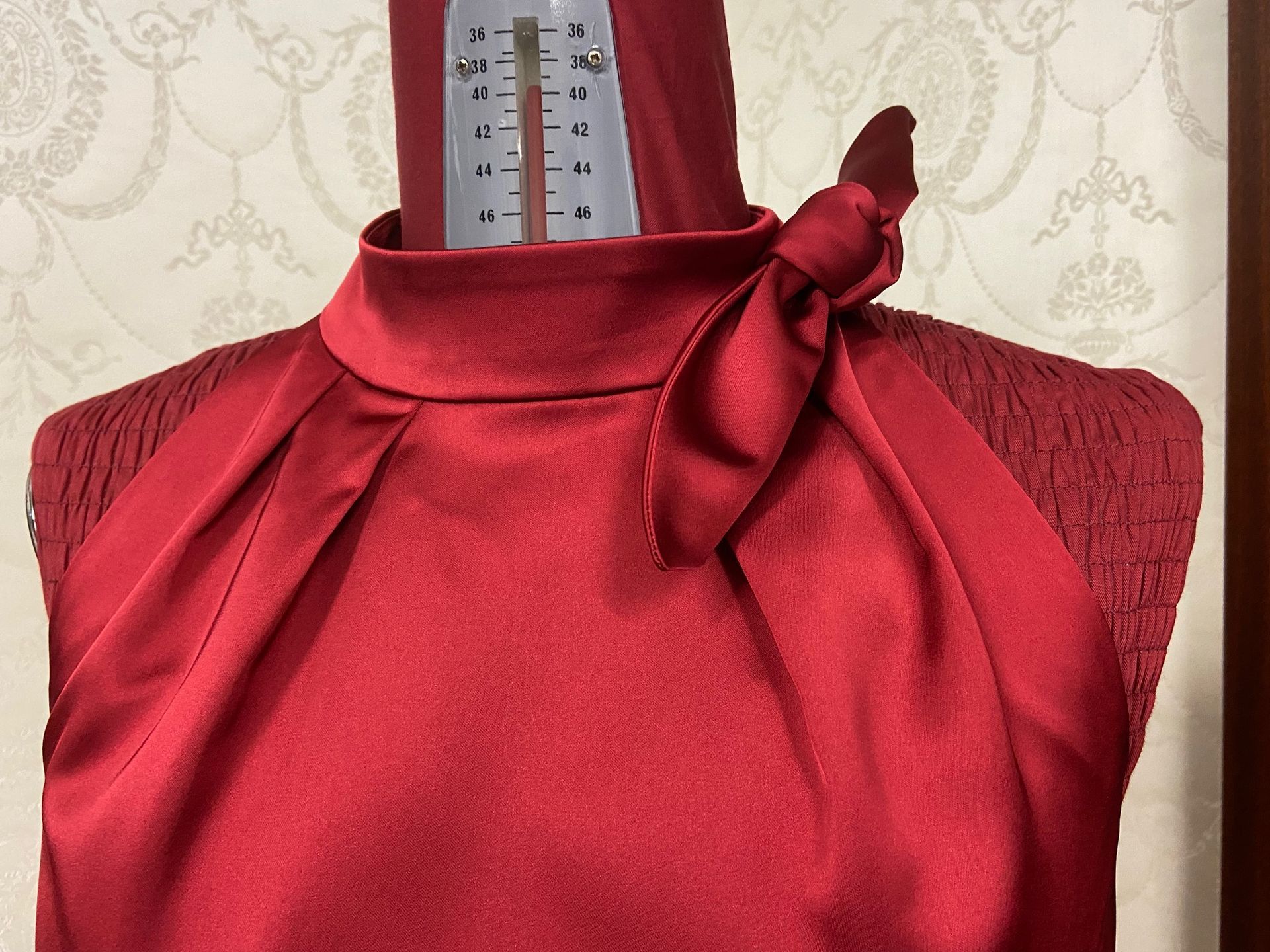 Ein rotes Kleid hängt auf einer Schaufensterpuppe mit einem Lineal darauf