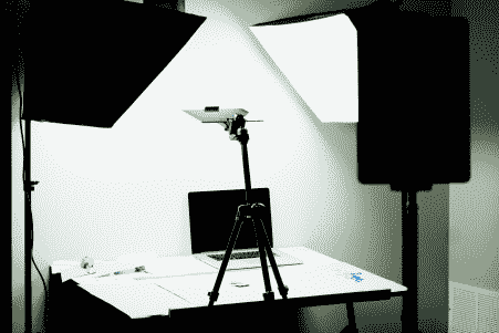 A laptop is on a tripod in a photo studio