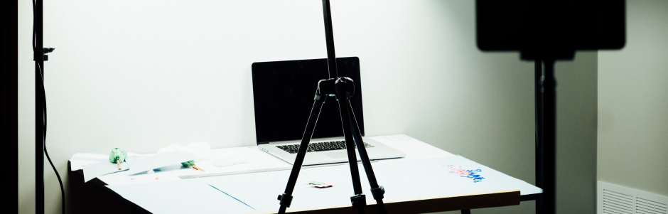 A laptop computer is on a tripod on a table.