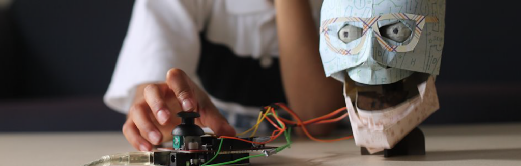 A person is playing with a robotic head on a table.