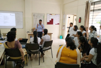 A man is giving a presentation to a group of people in a classroom.