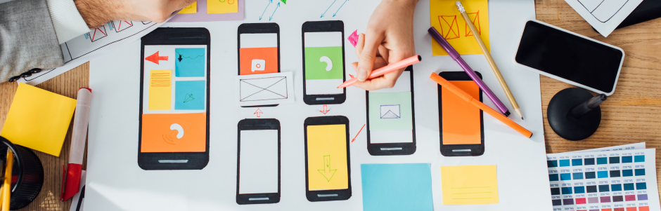 A person is sitting at a table working on a mobile app.