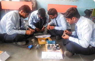 A group of young men are sitting on the floor working on a project.