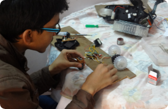 A boy wearing glasses is working on a circuit board