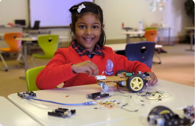 A little girl is sitting at a table playing with a toy car