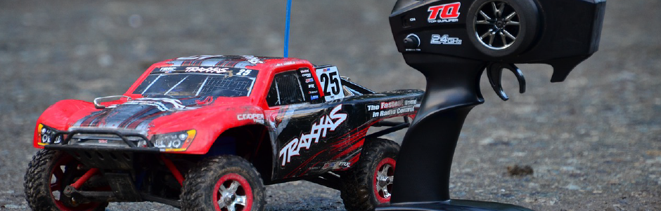 A red rc truck is sitting on top of a remote control.