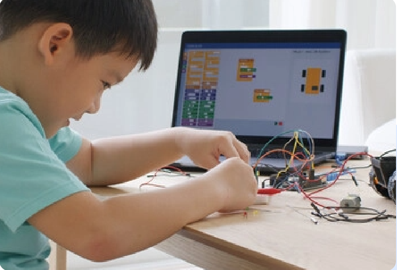 A young boy is sitting at a table working on a laptop computer.